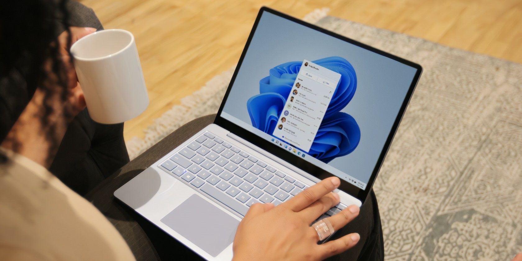 A woman working on her Windows laptop while drinking coffee